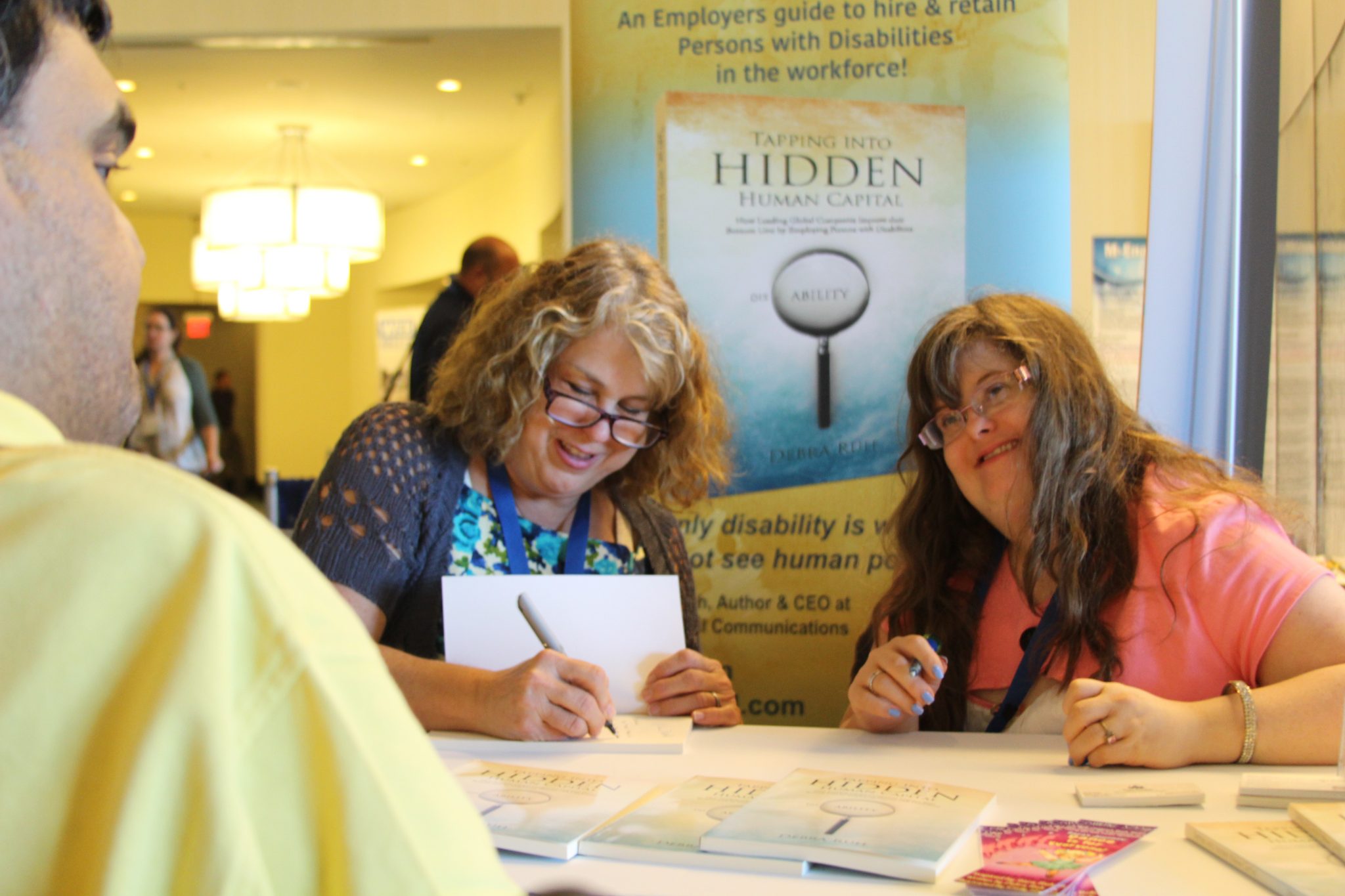 Debra Ruh (L) and daughter, Sara (R) are all smiles while Debra signs her book for a fan — published by G3ict.